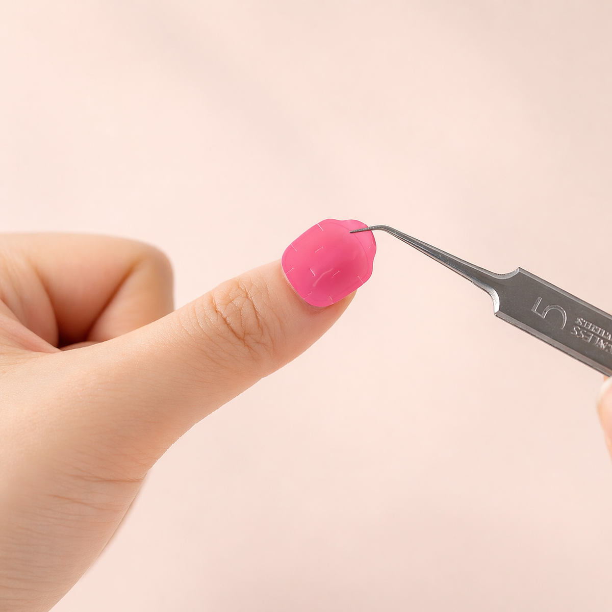 Applying a pink adhesive gel tab to a natural nail with tweezers
