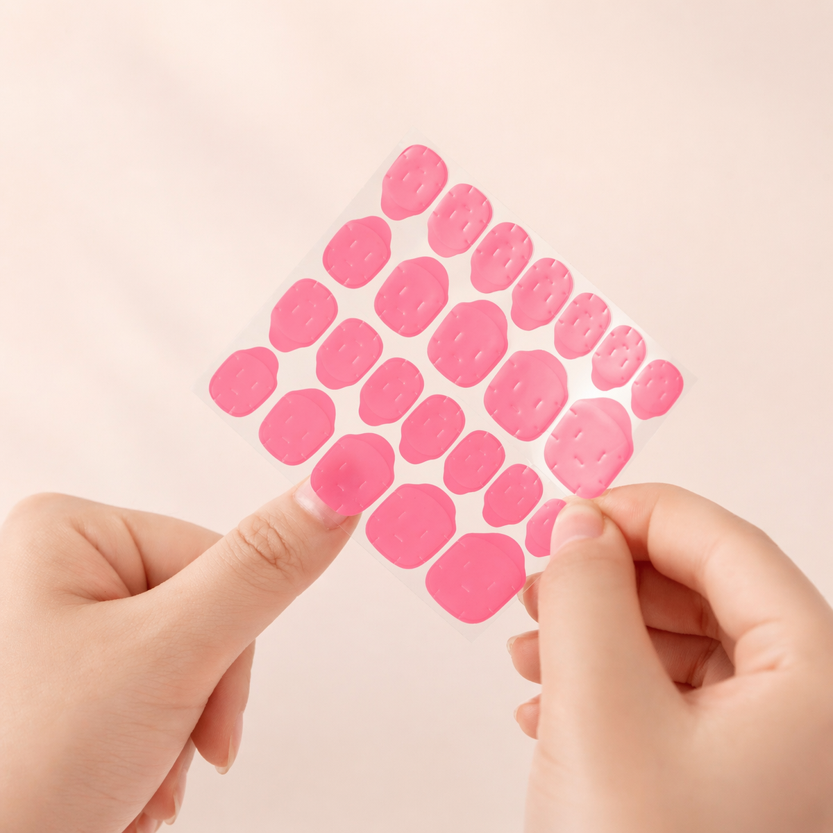 Sheet of pink adhesive gel tabs held with both hands